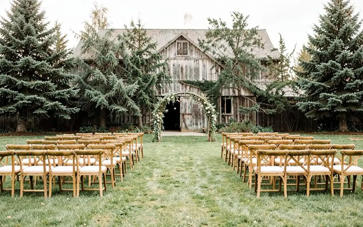 Barn venue lawn set with rows of wooden chairs for an outdoor ceremony